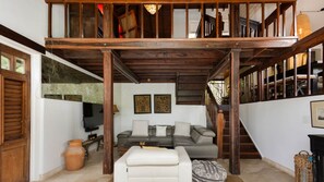 Una sala de estar con sofá, mesa de centro, televisor y una escalera.