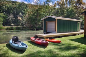 A dock with kayaks and a shed by a calm lake. - Reel Good Times on Mill Creek Waterfront Fishing & Family Retreat with Kayaks (Scottsboro)