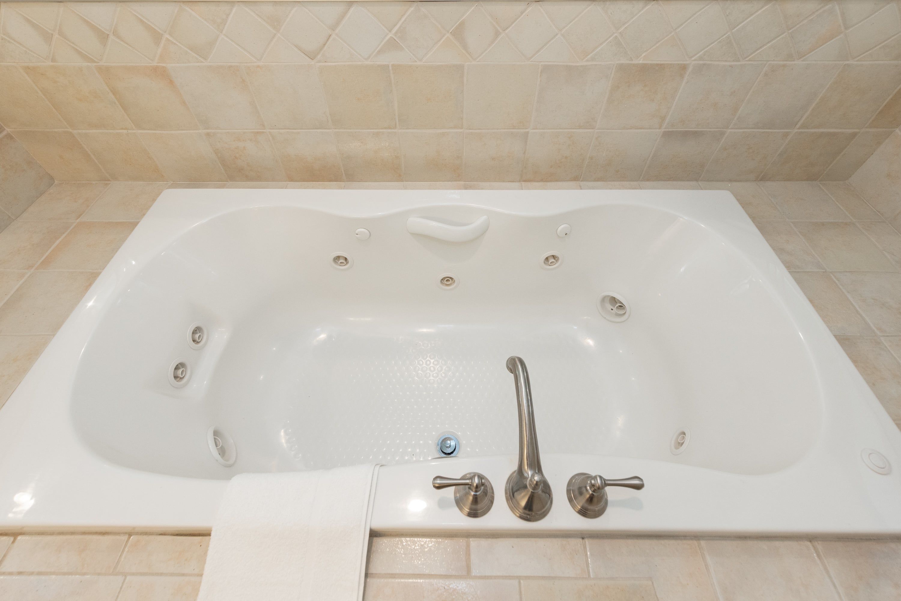 Une baignoire blanche, dotée d’un seul robinet et d’une douchette, placée devant un mur carrelé.