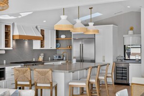 A modern kitchen with a central island, stainless steel appliances, and pendant lighting. - Moonlight Dream - 4 Bedroom Panoramic Ocean Views (Encinitas)