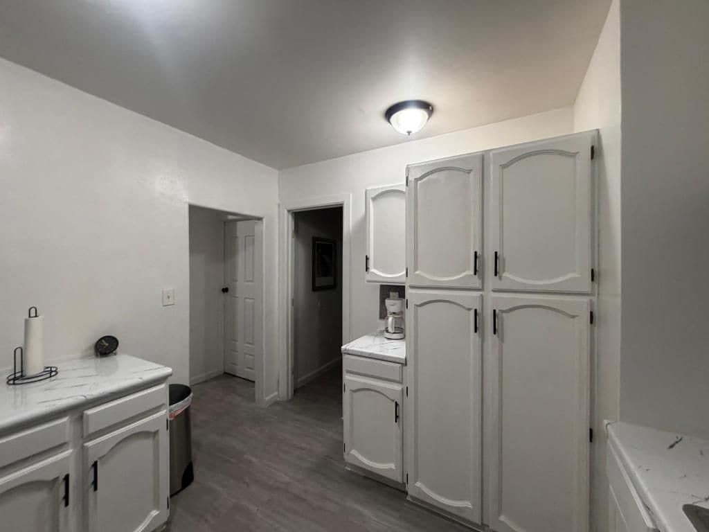 A kitchen with white cabinets, a marble countertop, and a ceiling light fixture.