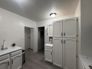 Cocina con armarios blancos, encimera de mármol y una lámpara en el techo.