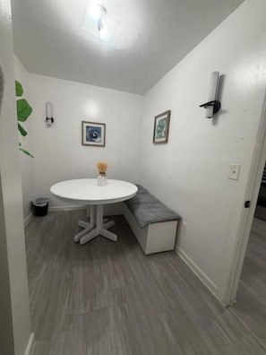 Una habitación pequeña con una mesa redonda, un banco y dos cuadros en la pared.