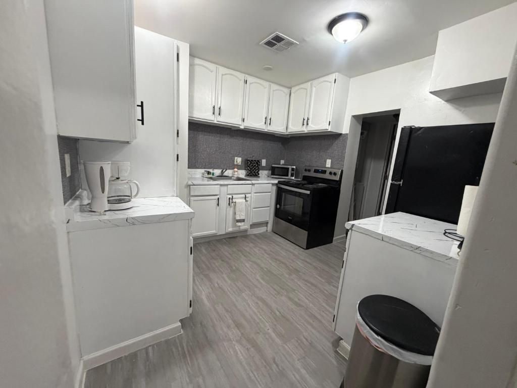 A compact kitchen with white cabinets, a microwave, an oven, and a coffee maker.