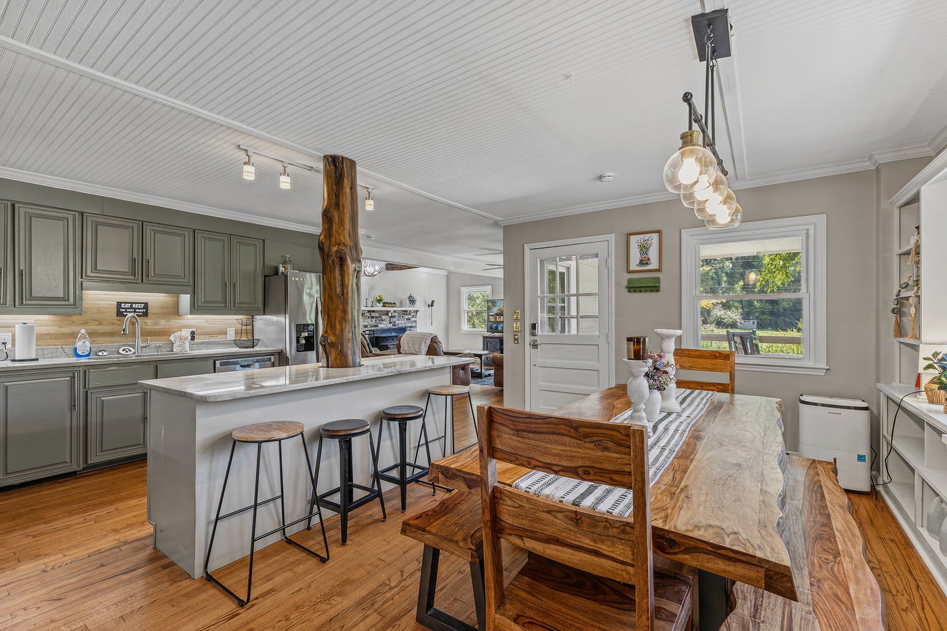 A modern kitchen with a central island, bar stools, and a dining table with chairs.