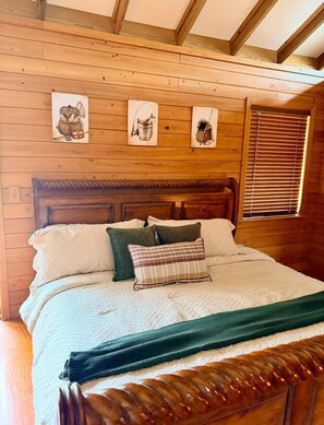 A wooden-paneled room with a bed, pillows, and a headboard. - Peaceful Riverfront Cabin with Screened Porch & Fishing! (Live Oak)