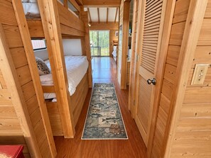 Un couloir étroit en bois, avec des lits superposés d’un côté et une porte de l’autre.