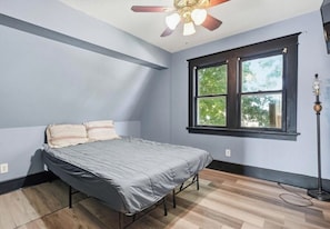 A bedroom with a bed, a ceiling fan, a window, and a floor lamp. - 4-bedroom house close to downtown and new casino 14 mins to data center WiFi (Cedar Rapids)