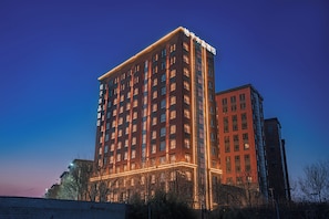 Edifício de hotel com vários andares, letreiros iluminados e vista clara do céu.