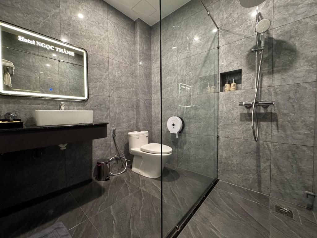 A modern bathroom with a glass-enclosed shower, a white sink, and a toilet.