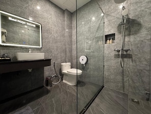 Une salle de bain moderne avec une douche à parois de verre, un lavabo blanc et des toilettes.