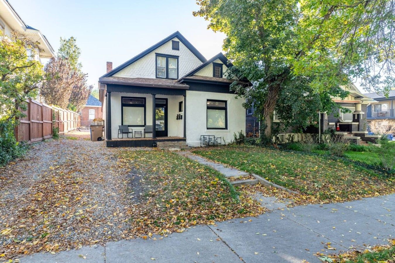 A two-story house with a front porch, a small garden, and a pathway leading to the entrance.