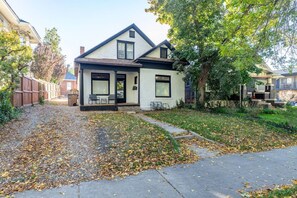 A two-story house with a front porch, a small garden, and a pathway leading to the entrance. - The University District Hideaway | Spacious 3BR (Salt Lake City)