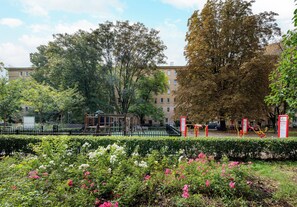 A park with playground equipment, a building in the background, and a variety of trees. - Metro Politechnika Central Apartment (Warszawa)