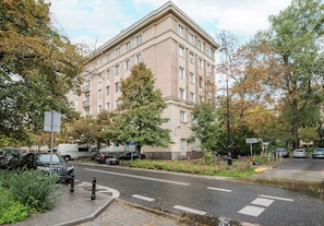 A multi-story building with a flat facade, surrounded by trees and parked cars. - Metro Politechnika Central Apartment (Warszawa)