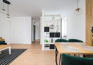 A modern interior with a dining area, a white bookshelf, and a hallway. - Metro Politechnika Central Apartment (Warszawa)