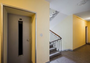 A hallway with a door, a staircase, and a light fixture. - Metro Politechnika Central Apartment (Warszawa)