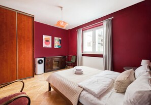 A hotel room with a bed, a radiator, a heater, a wardrobe, a chair, a desk, and a window with curtains. - Marszałkowska Classic Apartment (Warszawa)