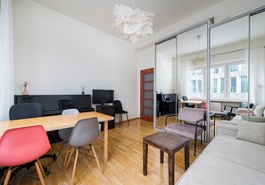A modern office space with a wooden table, chairs, a sofa, and a large mirror reflecting the room. - Marszałkowska Classic Apartment (Warszawa)