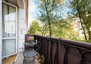 A balcony with a metal table and chairs, a potted plant, and a view of trees and buildings. - Nowolipki Serene Apartment (Warszawa)