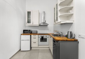 A compact kitchen with white cabinetry, a microwave, a toaster, a kettle, and a dishwasher. - Dietla Avenue Homely Apartment (Kraków)
