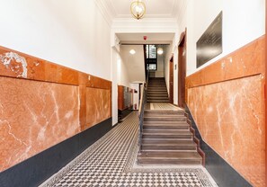A hallway with marble walls, a patterned floor, and a staircase leading to a second floor. - Dietla Avenue Homely Apartment (Kraków)