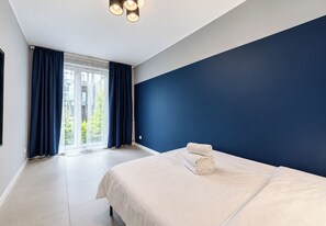Een slaapkamer met een bed en uitzicht op het omliggende landschap, met een blauwe wand.