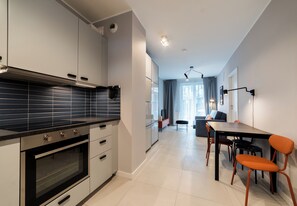 Een moderne keuken met een inbouwoven en een eethoek met een tafel en stoelen.