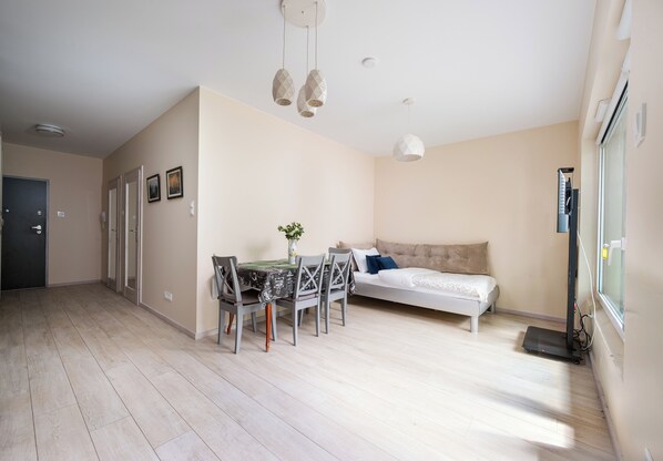 A modern bedroom with a bed, bedside table, and a dining area with chairs and a table. - Kołacińska Riverside Comfort Apartment (Warszawa)
