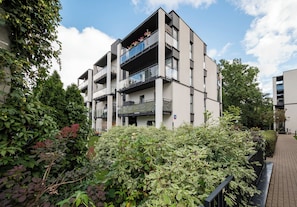 A multi-story residential building with balconies, surrounded by dense greenery. - Kołacińska Riverside Comfort Apartment (Warszawa)