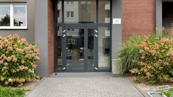 Une entrée moderne avec une porte en verre, un mur en briques et une plaque numérotée.