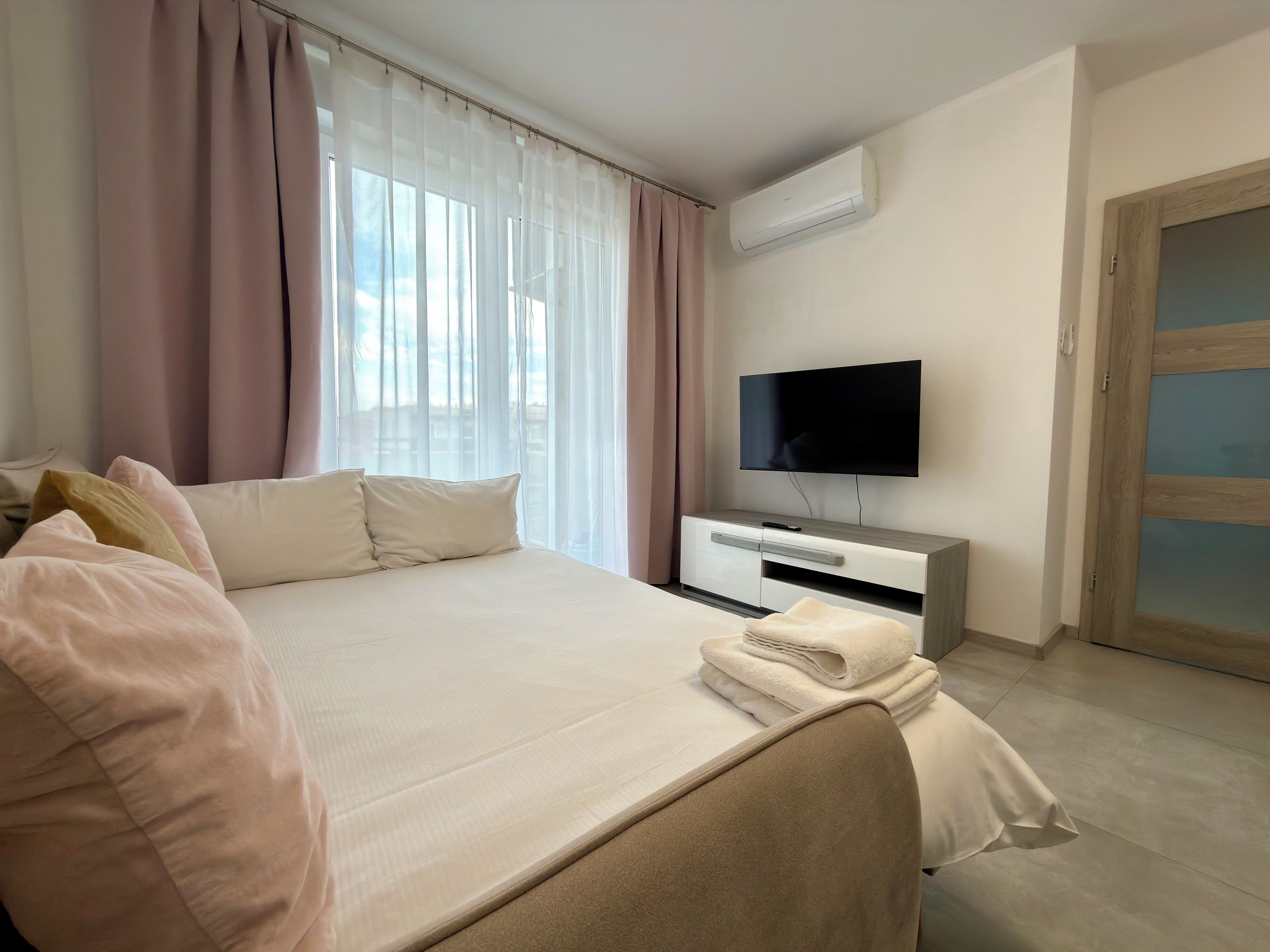 Hotellihuone, jossa on sänky, televisio, vaatekaappi ja ovi.