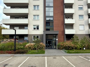 A multi-story residential building with balconies, a central entrance, and a parking area in front. - Czartoryskiego Modern Apartment (Wrocław)