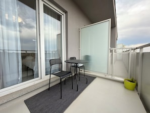 Un balcon avec une chaise, une petite table et un pot de fleurs.