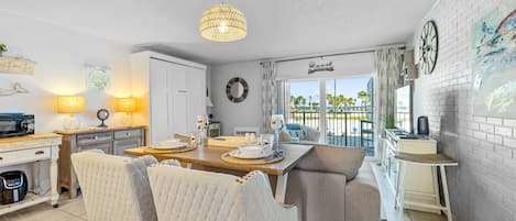 A well-lit kitchen with a dining area, a large window with a view, and a clock on the wall.