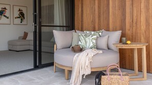 A modern living room with a grey sofa, wooden side table, and a wicker basket. - Alkina | A Soulful Conjola Park Retreat (Conjola Park)