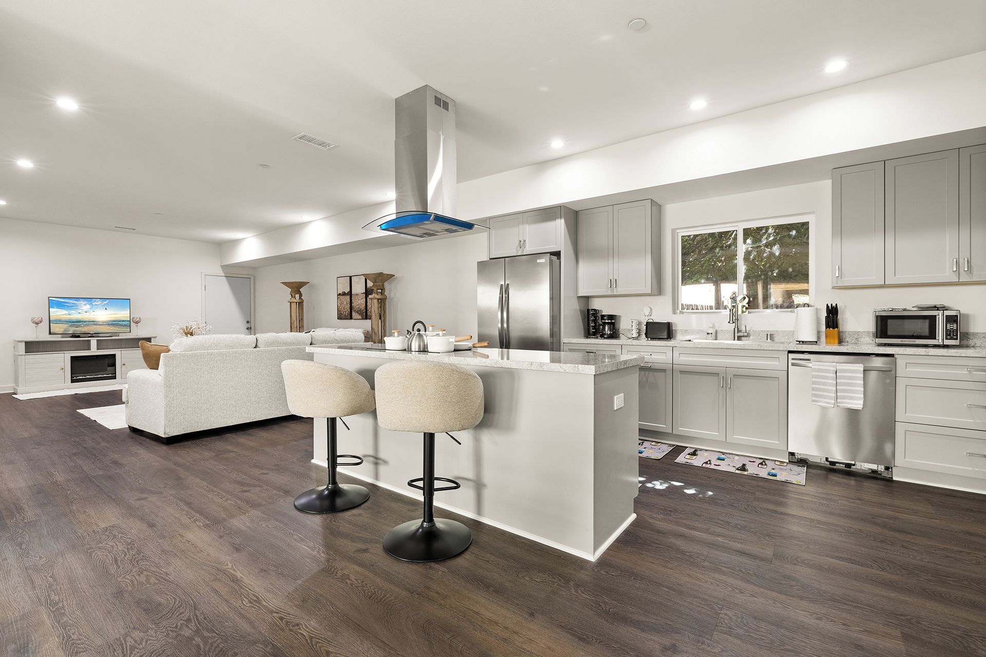 A modern kitchen with a central island, stainless steel appliances, and a dining area with bar stools.
