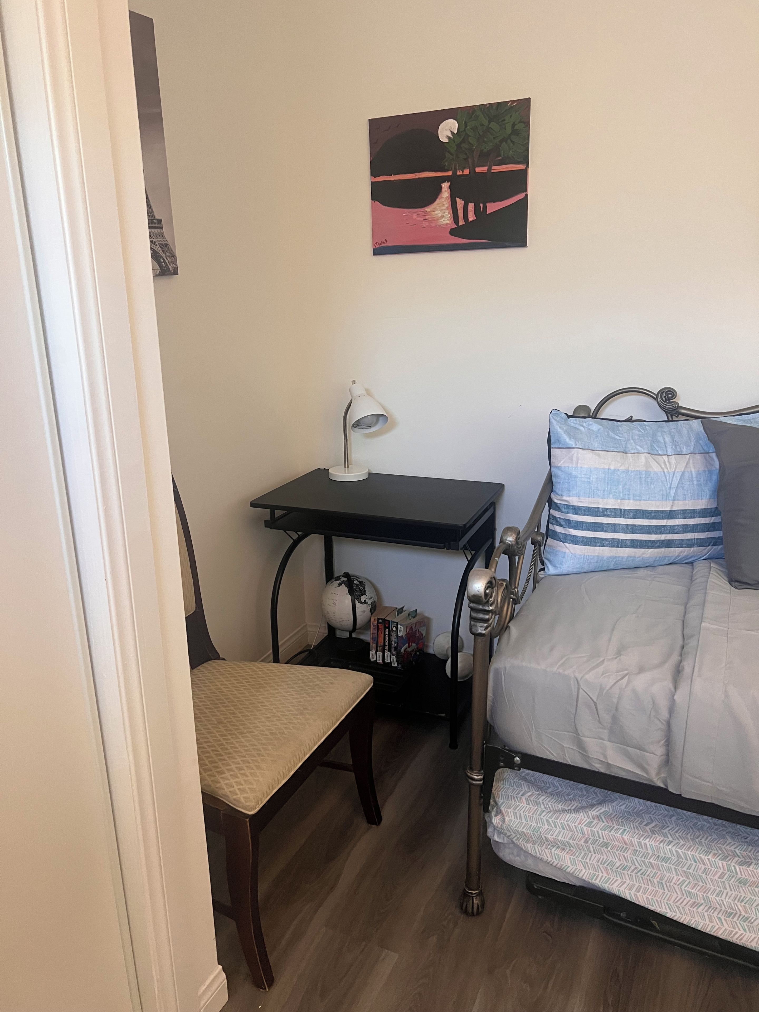 A compact room with a bed, a desk, a chair, and a globe.