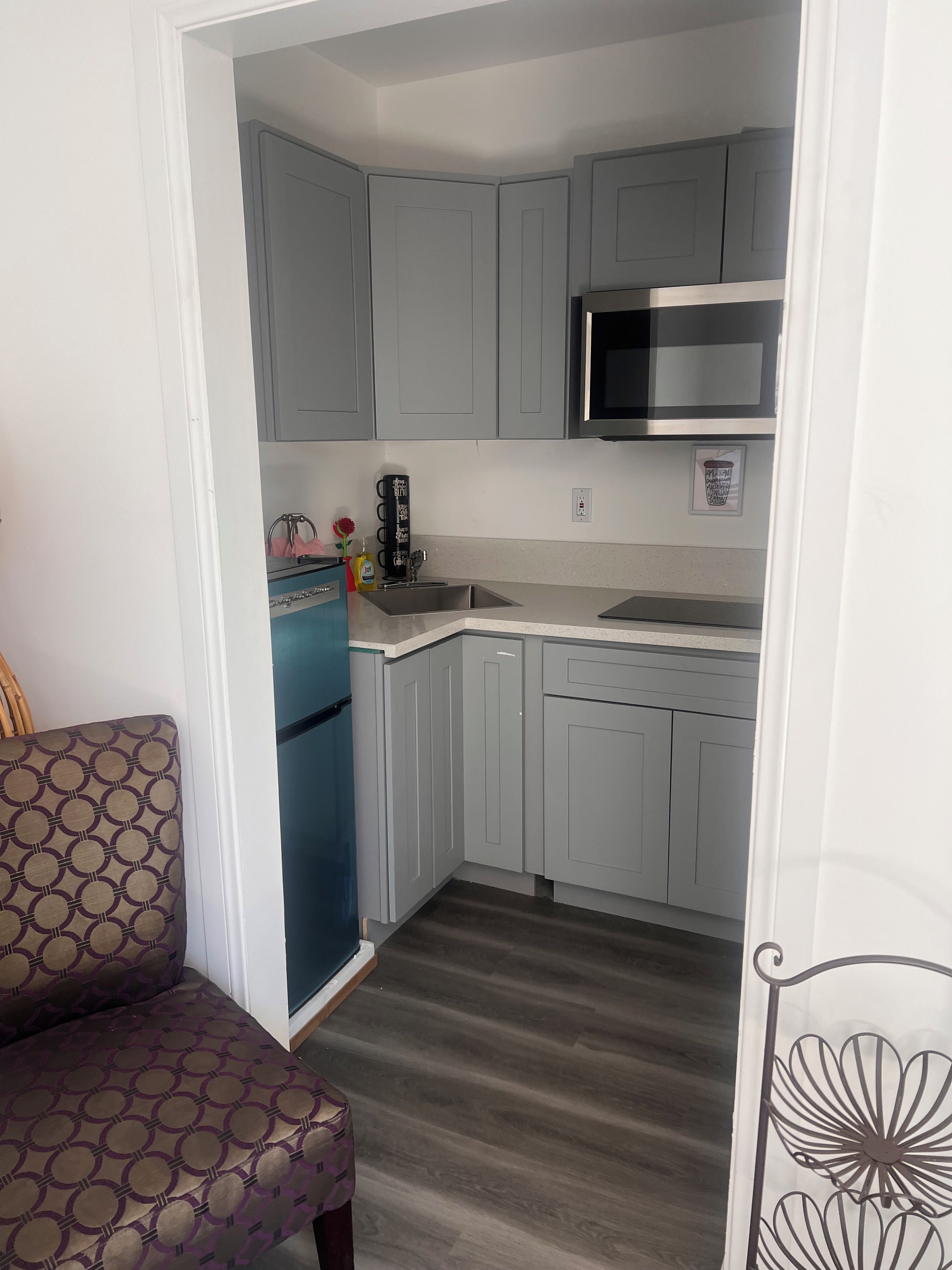 A compact kitchen with grey cabinets, a stainless steel sink, and a microwave.