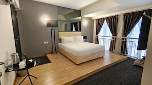 Une chambre d’hôtel avec un lit, une table de chevet, une lampe, un miroir, une fenêtre avec des rideaux et un petit balcon.