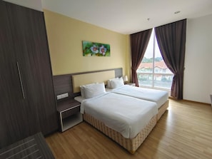 Une chambre d’hôtel avec deux lits, une table de chevet, une armoire et une fenêtre avec des rideaux.
