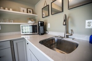A kitchen with a stainless steel sink, a coffee maker, and a microwave. - Wall Street Suites 4 | Queen Studio near SIU (Carbondale)