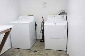 A laundry room with two white washing machines and a table. - Wall Street Suites 4 | Queen Studio near SIU (Carbondale)