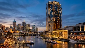 Silhueta urbana com um hotel de destaque chamado 'Crown Melbourne' e um rio com barcos.