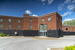 A brick building with a large glass entrance and a black wall to the left. - Wall Street Suites 2 | Queen Studio near SIU (Carbondale)