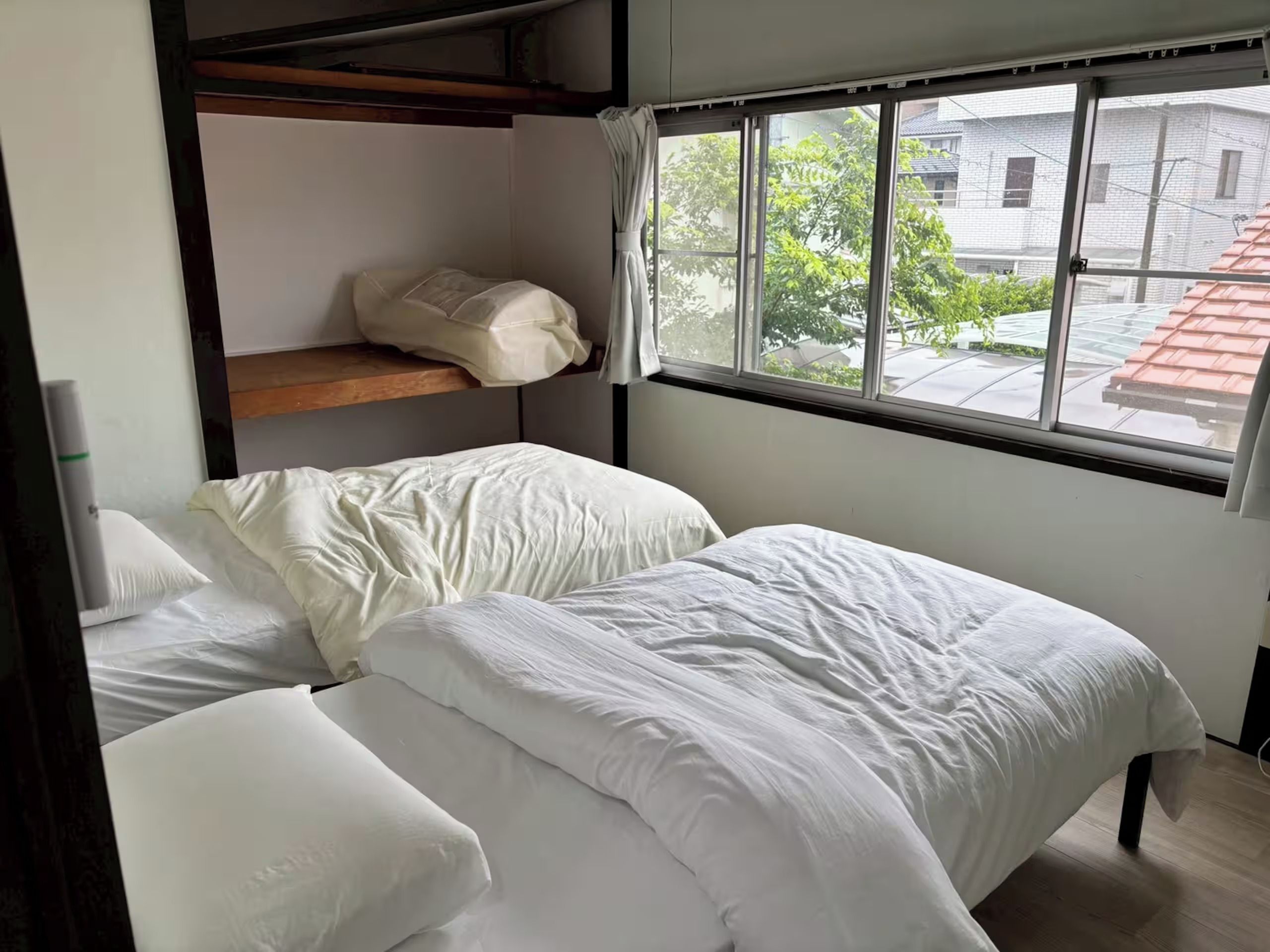 Ein Zimmer mit Etagenbetten, einem Fenster mit Aussicht und einem Vorhang.