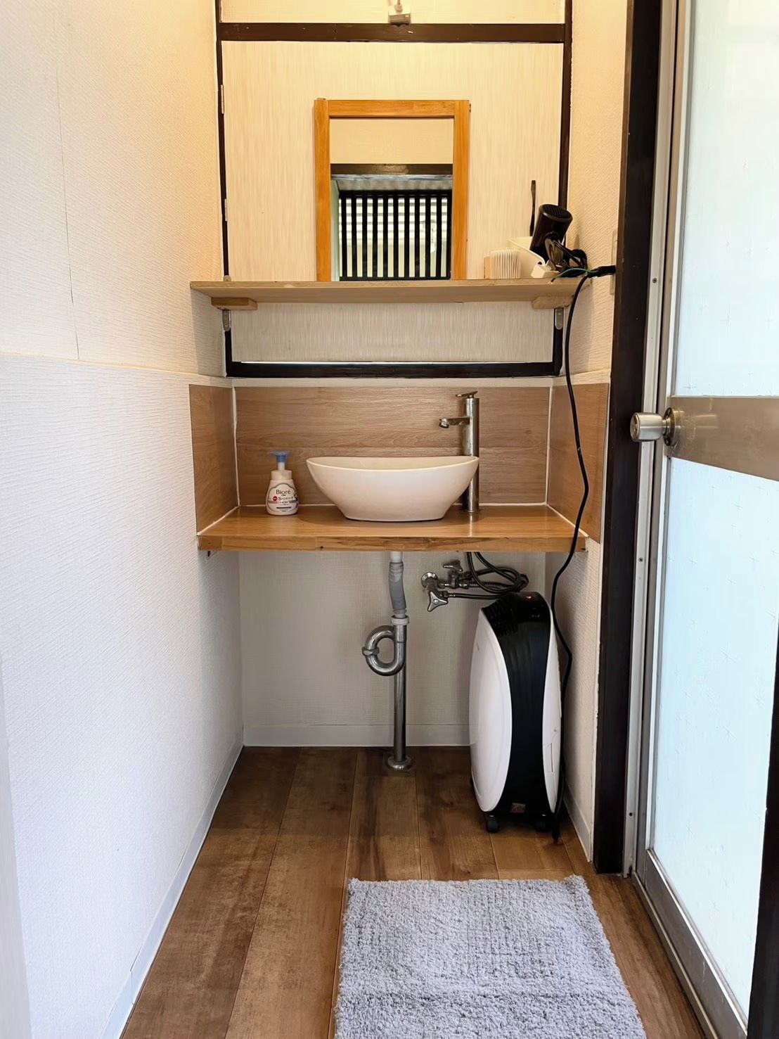 Ein kleines Badezimmer mit einem Holzkosmetikschrank, einem weißen Waschbecken, einem Handtuchhalter und einer Toilette.