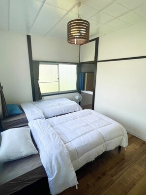 Una habitación con cama, ventilador y ventana.