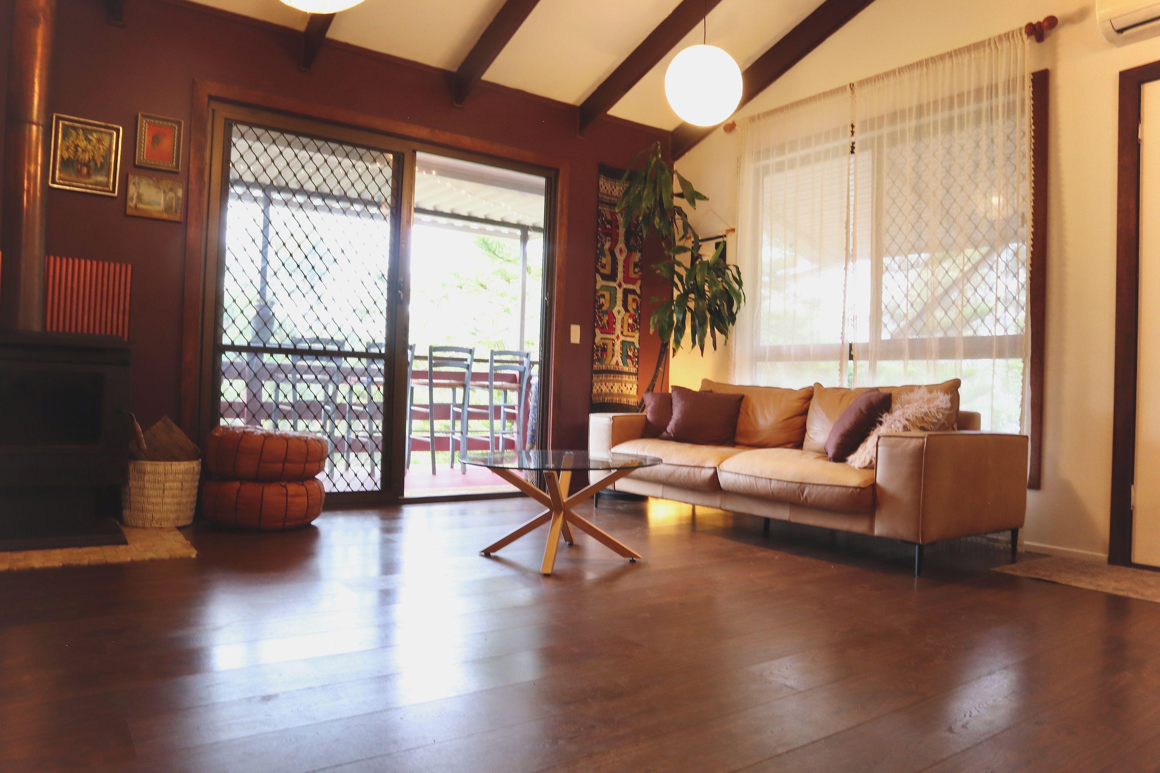 A living room with a sofa, a glass coffee table, a fireplace, and a sliding glass door leading to an outdoor area.