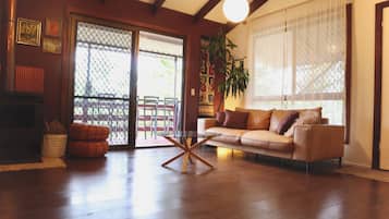 A living room with a sofa, a glass coffee table, a fireplace, and a sliding glass door leading to an outdoor area.